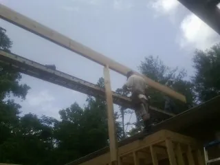 Carpenter setting a ridge beam over a new addition frame — Ice Dam Removal by Roofing Brothers in Charleston