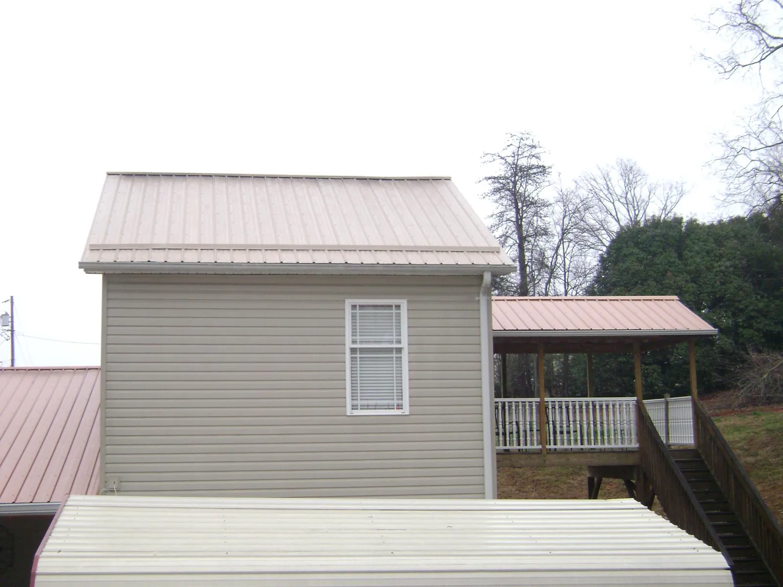 Tan metal roofs on a two story addition and attached porch, from a Roof Replacement job in Charleston